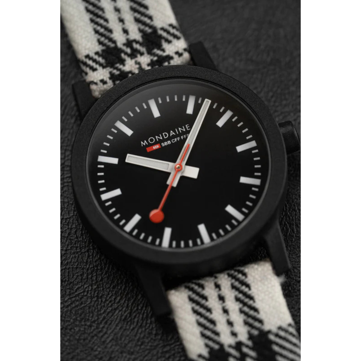 Ladies quartz wristwatch close-up with black dial, red second hand, and tartan strap