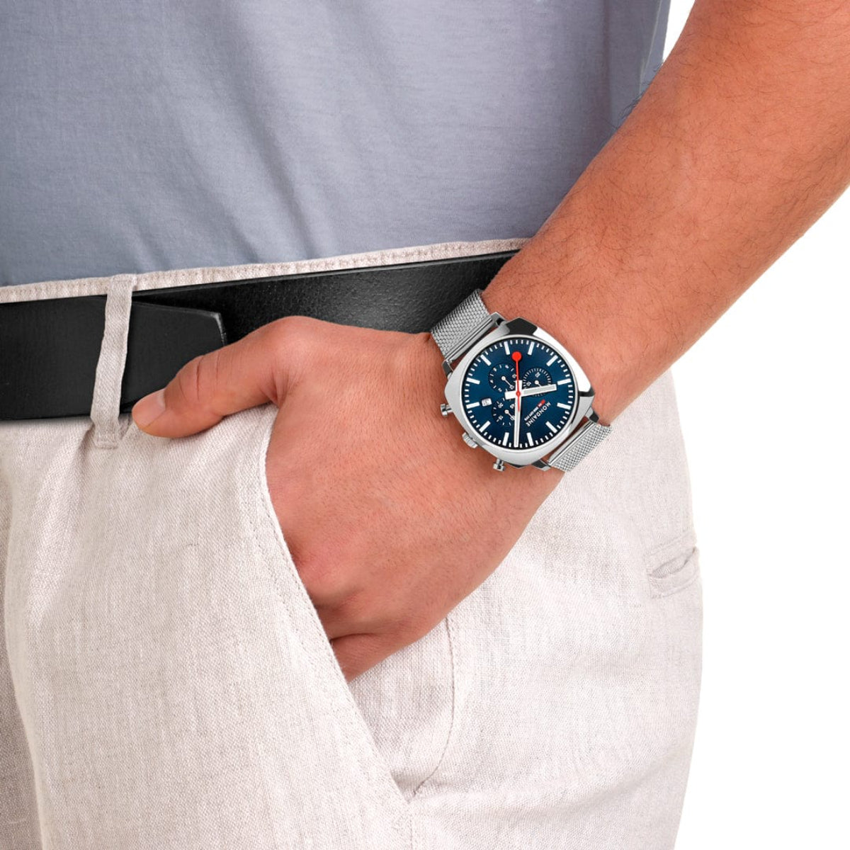 Square blue dial watch on wrist with navy textile strap and silver case