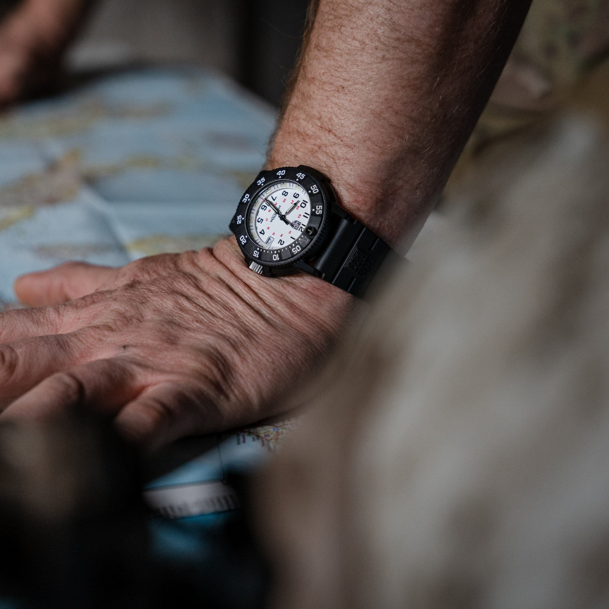Men's quartz dive watch on wrist with black bezel and white dial markers