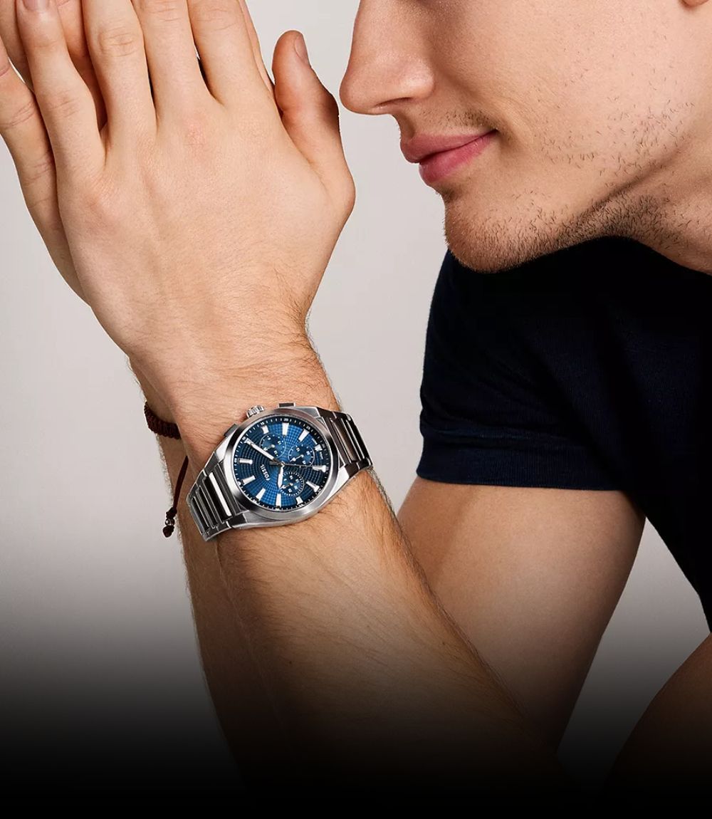 Fossil mens blue chronograph watch worn on wrist with textured sunray dial and integrated stainless steel bracelet
