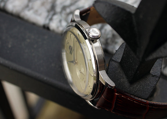 Side profile of an Orient dress watch showing the signed crown, polished stainless steel case, and dark brown crocodile leather strap