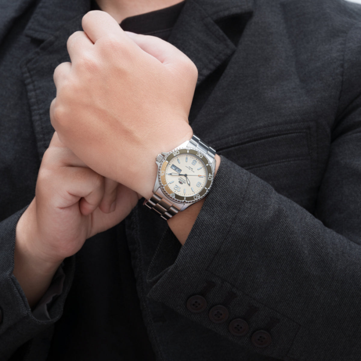 Men's automatic steel watch worn on wrist with ivory dial and day-date window