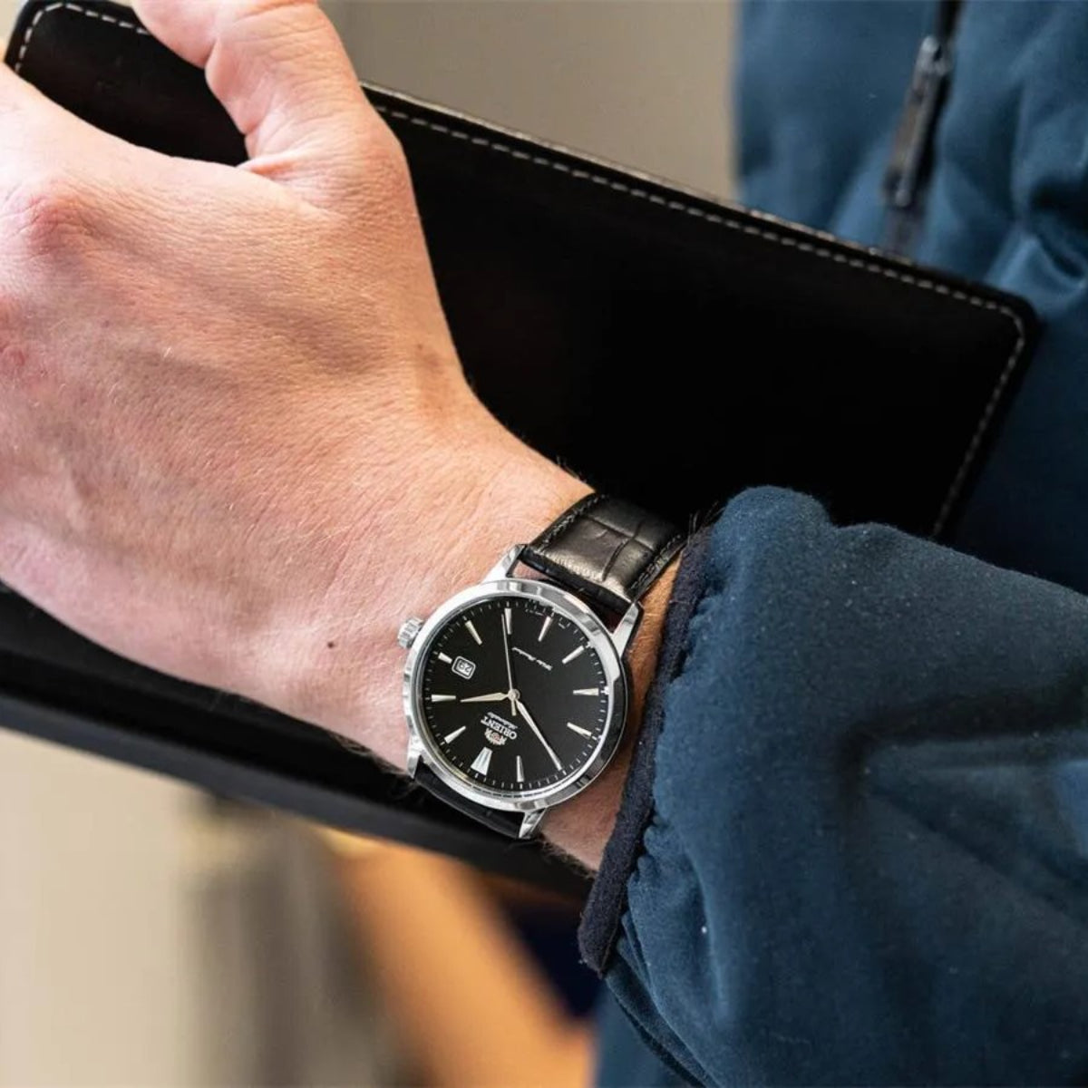 Orient Contemporary RA-AC0F05B30B on the wrist with black dial and leather strap with a blurred background