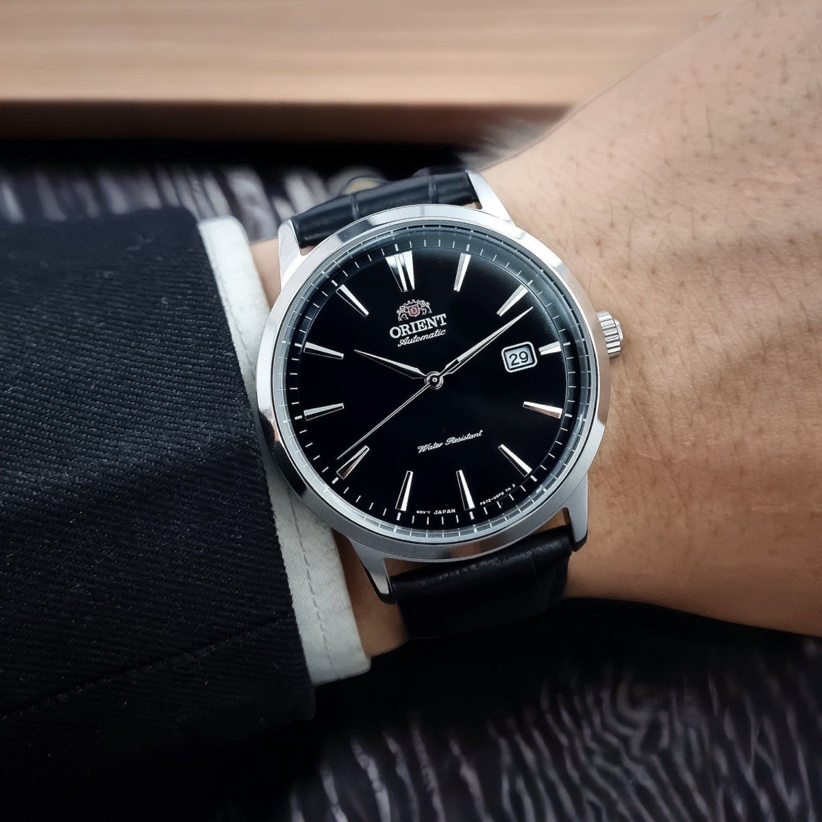 Men's 42mm automatic watch on wrist, black dial with date window, leather strap