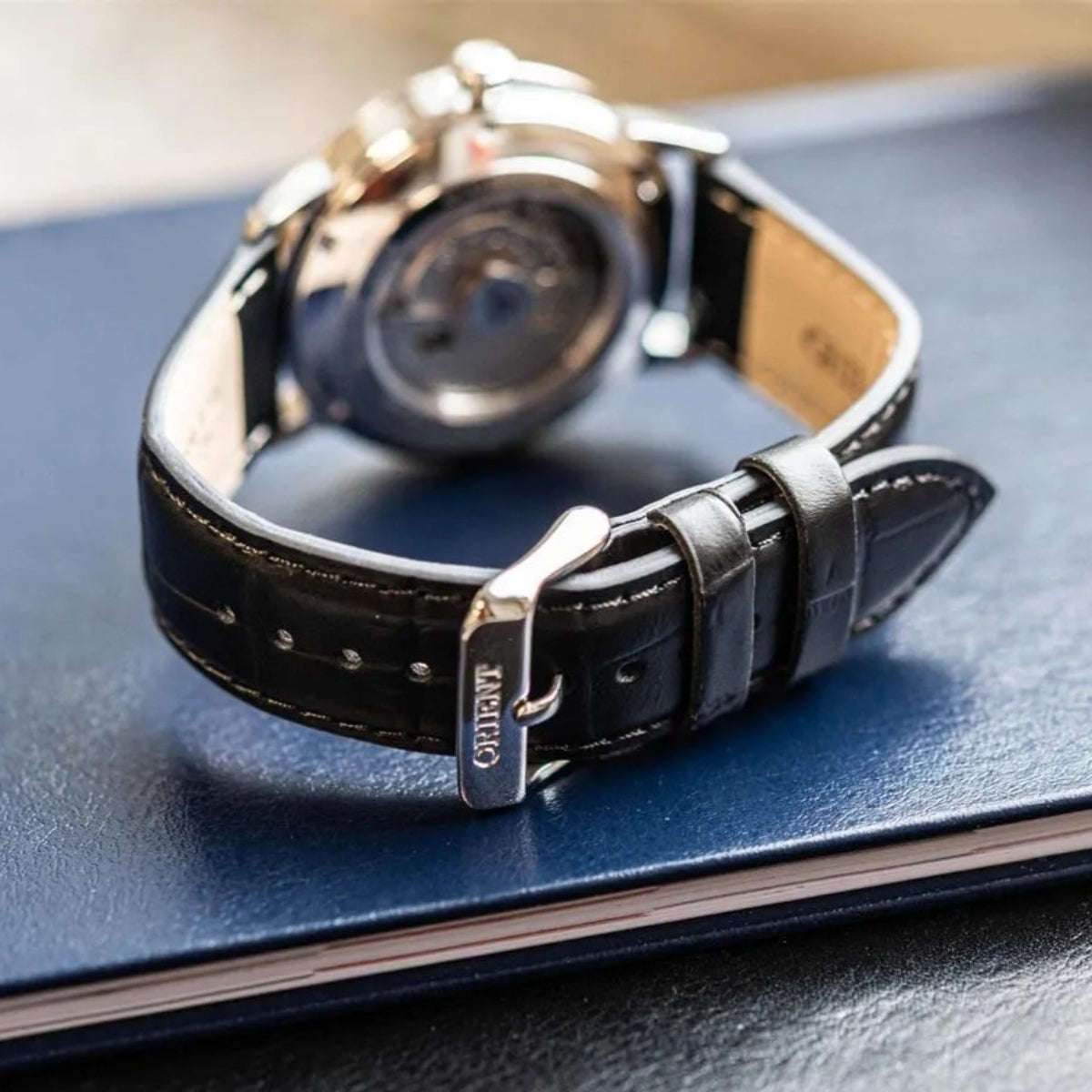 Orient Contemporary Symphony III automatic mens watch RA-AC0F05B30B with black leather strap on a blue surface
