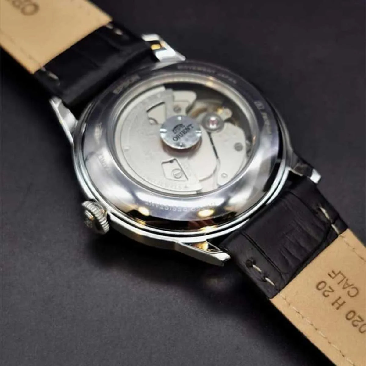 Orient Bambino RA-AC0M03S30B watch close-up showing inner mechanism through see-through case back and black strap