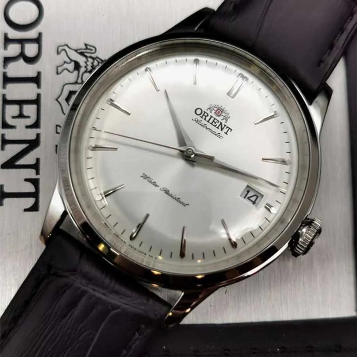 Orient Bambino automatic wrist watch with white dial, black leather strap, silver case, and date display