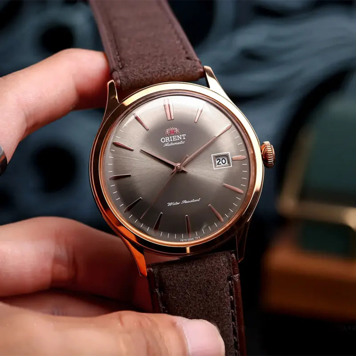 Orient Bambino RA-AC0P04Y30B held in hand highlighting bronze dial and rose gold tone finish