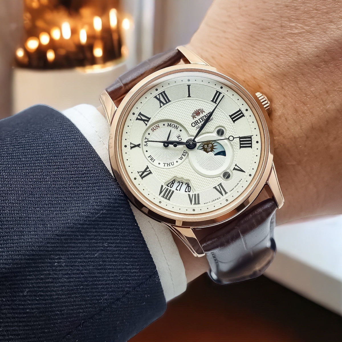 Orient Bambino Sun & Moon RA-AK0007S30B mens wristwatch styled on wrist with a champagne dial and brown leather strap
