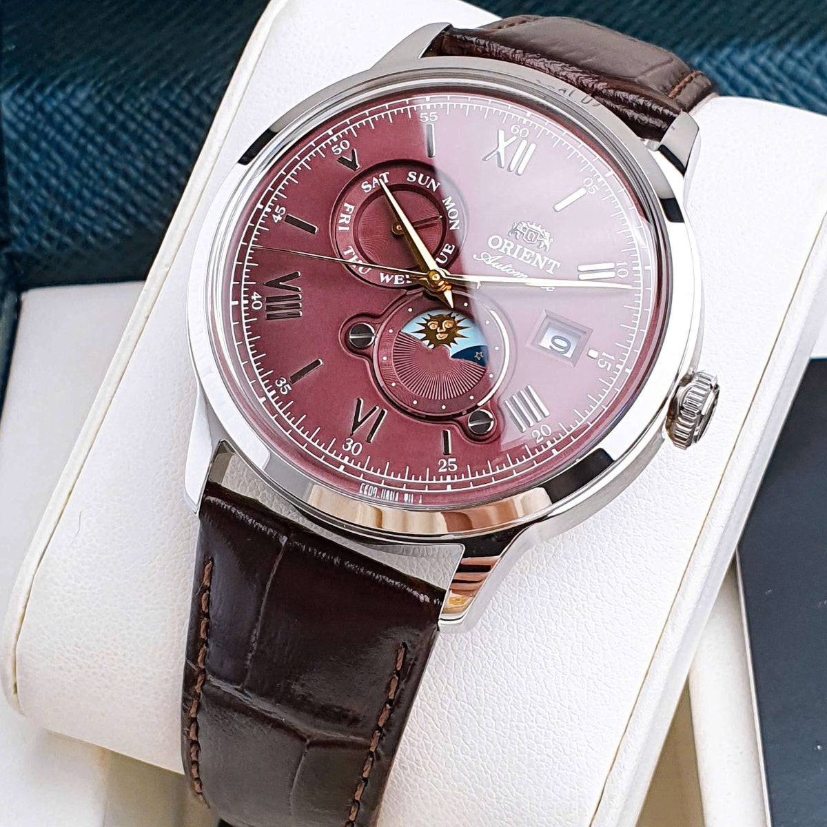 Angled view of Orient Bambino RA-AK0807R30B mens automatic timepiece with red dial resting in presentation box