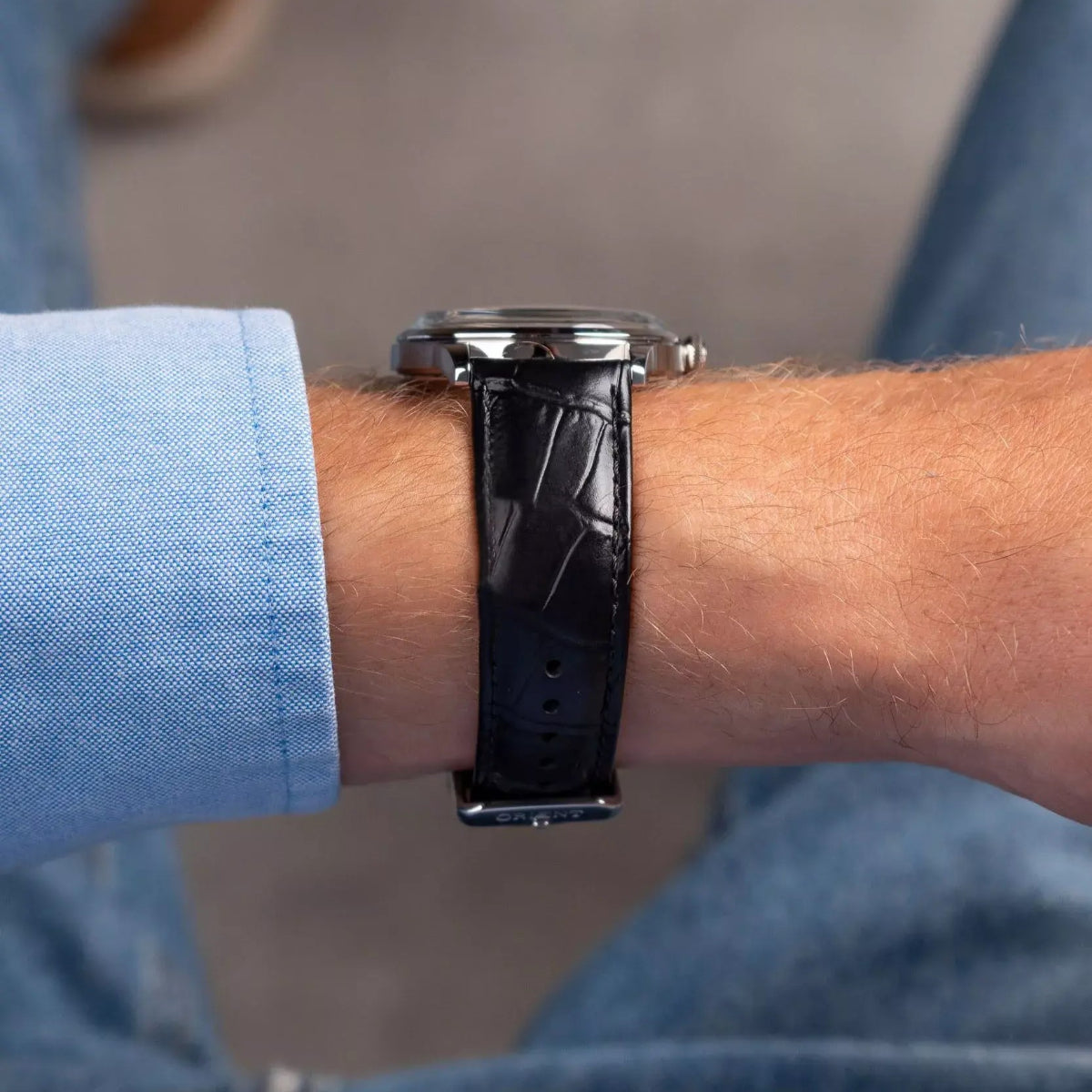 Orient Bambino watch on wrist, side view with black leather strap and metal case