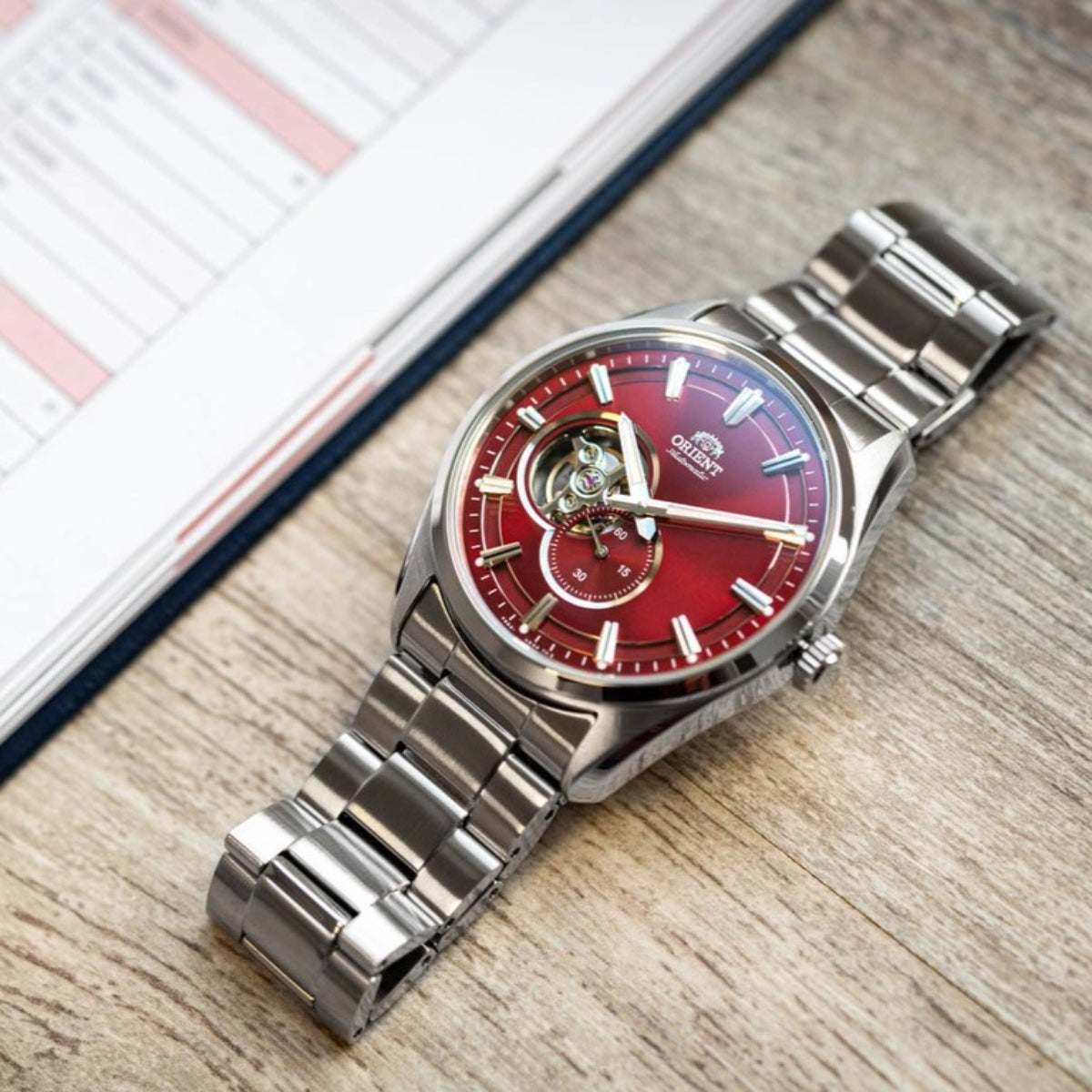 Men's automatic open-heart wristwatch with red dial and steel bracelet, side crown
