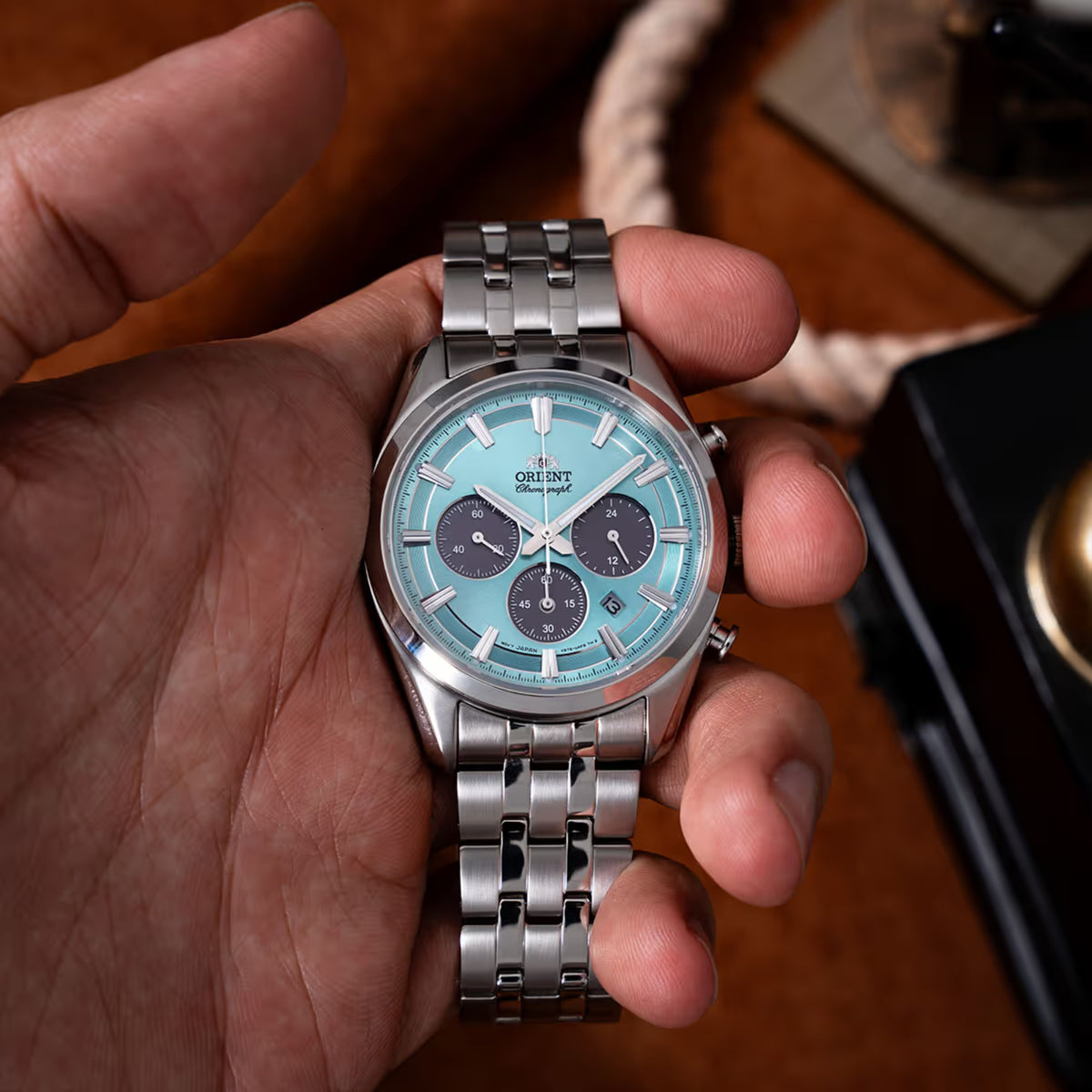 Solar chronograph wristwatch with light blue dial, steel case, and dark subdials.