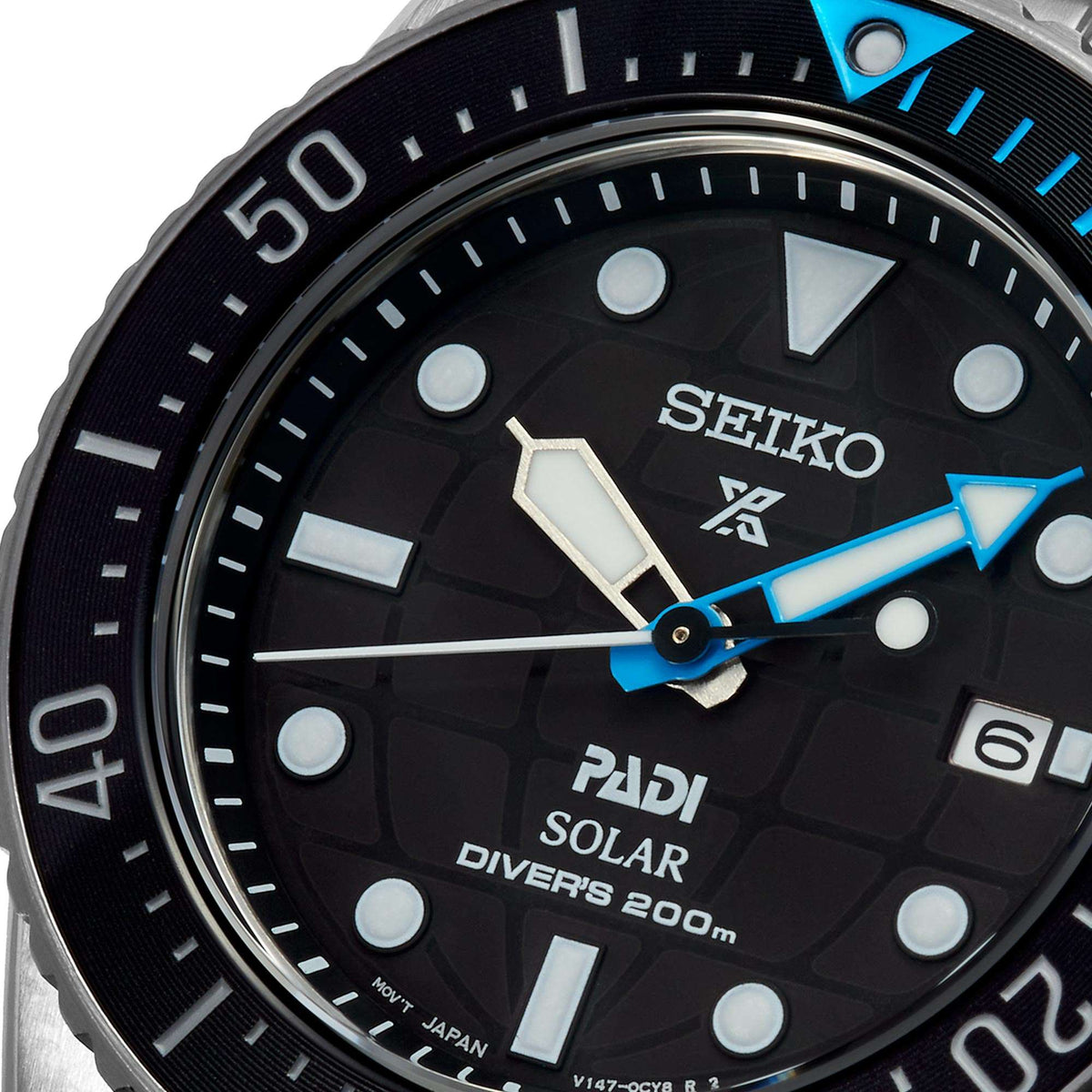 Close-up stainless solar dive watch dial with blue hands, markers, and PADI SOLAR text