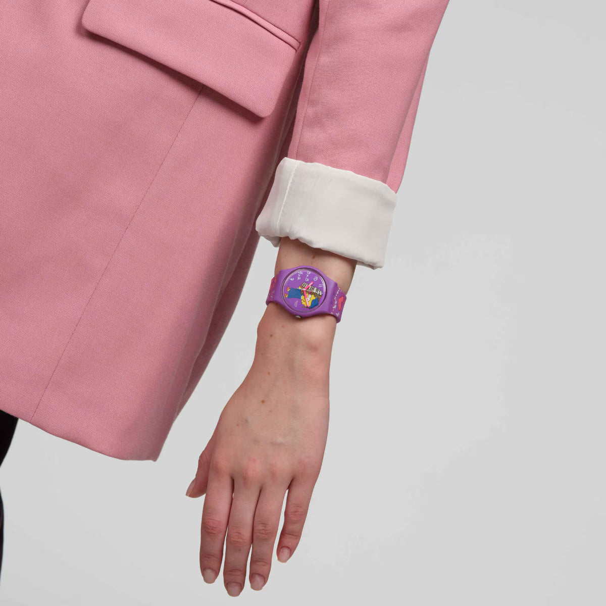 Purple Swatch silicone watch on wrist with Lisa dial and printed hearts and stars strap