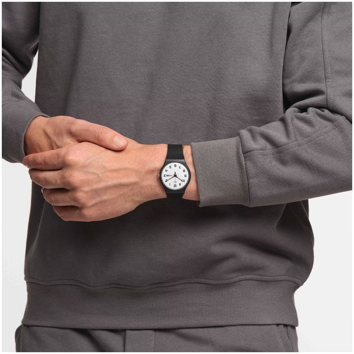 Unisex wristwatch on wrist with white dial and black strap, round case close-up.
