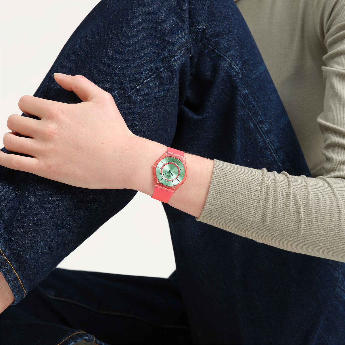 Mint dial silicone watch with coral-pink band on wrist with knit sleeve