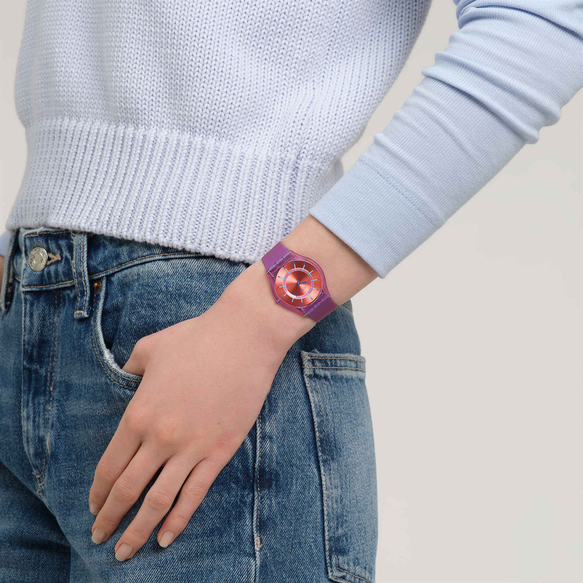 Purple silicone strap watch on wrist with orange-red dial and blue hands