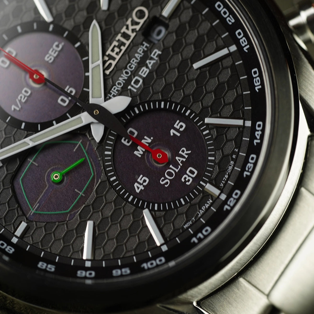 Solar chronograph close-up: black dial with solar subdial and red seconds, steel case