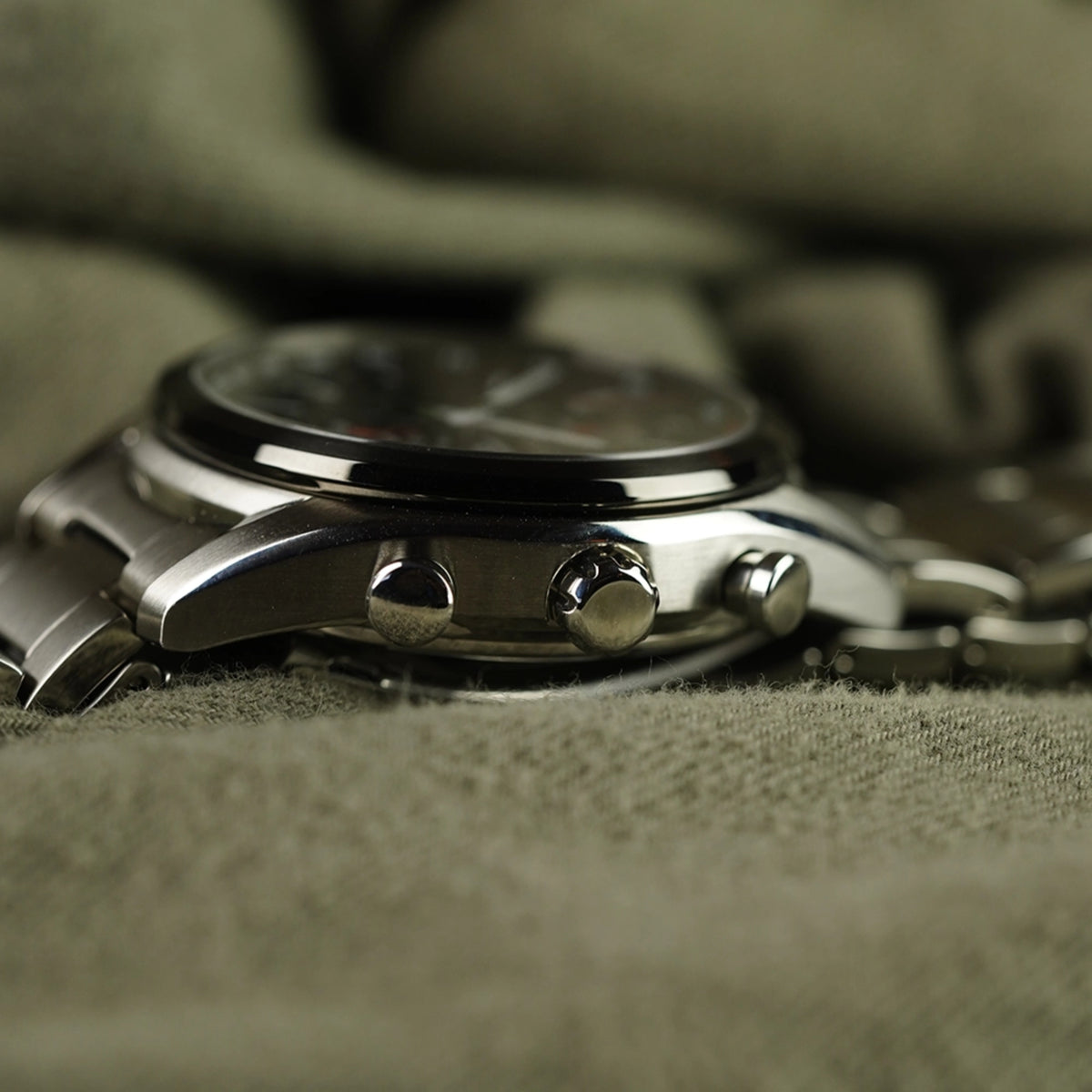 Solar chronograph watch side view showing crown and pushers on steel case