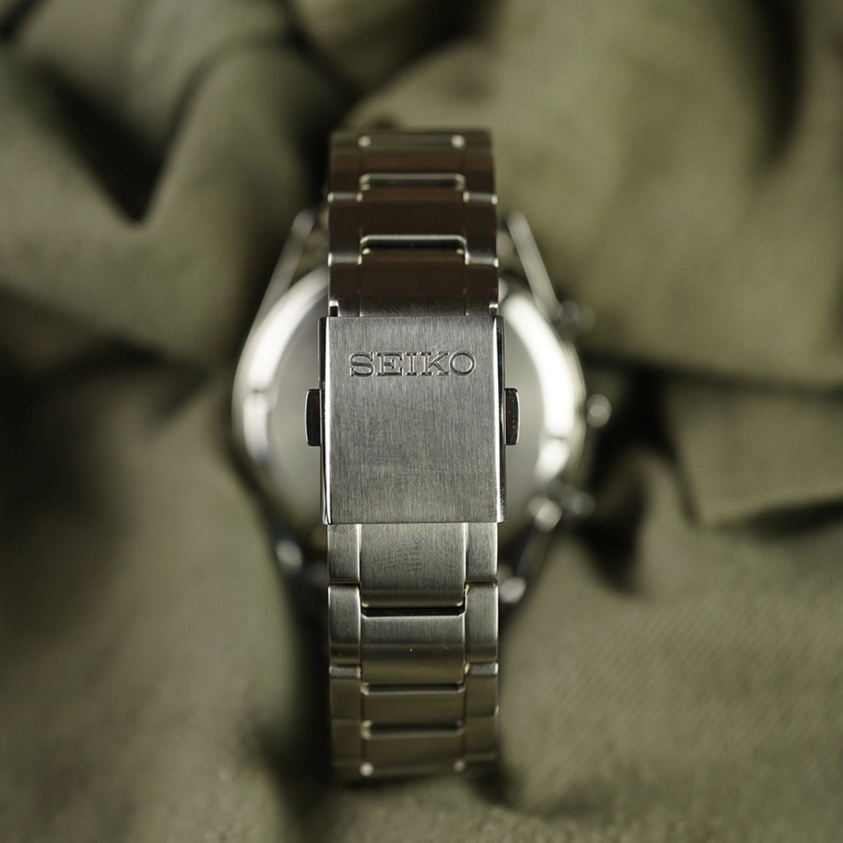 Steel watch bracelet with SEIKO logo on clasp, close-up side view
