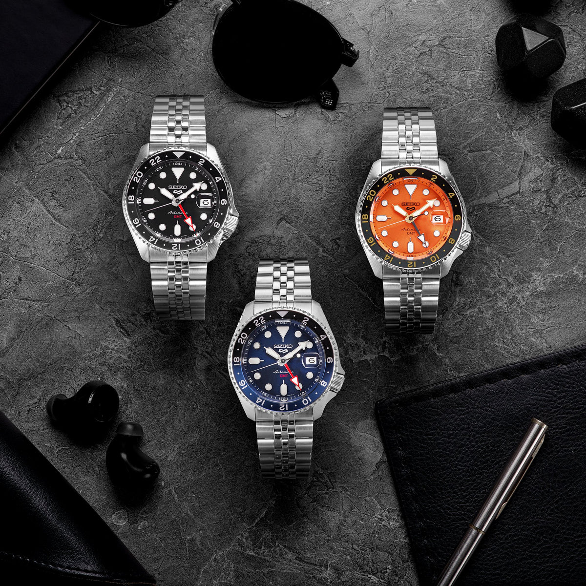 Men's Seiko GMT watch with orange dial, black bezel, and stainless-steel bracelet