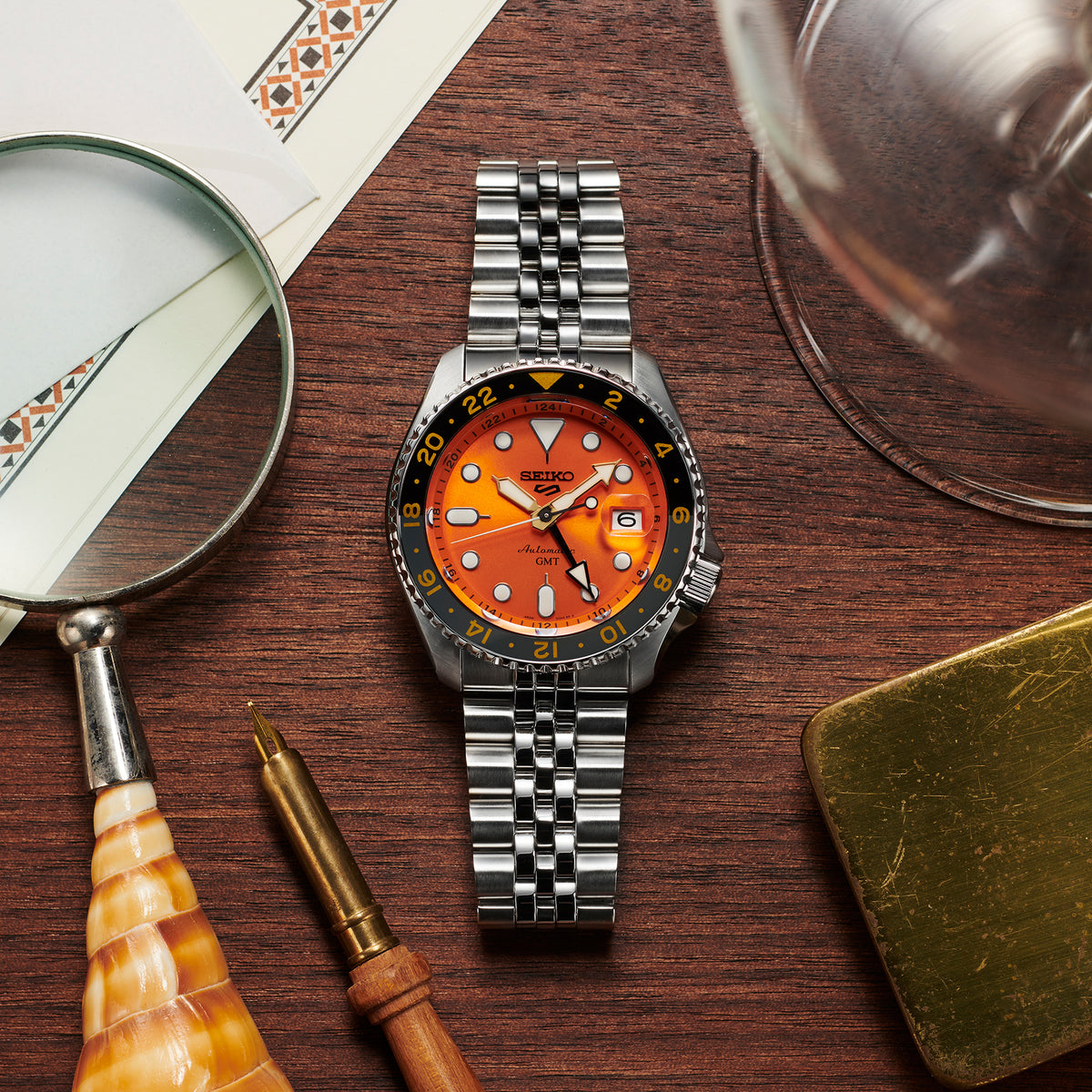 Men's Seiko GMT watch on a wooden surface with stainless-steel bracelet