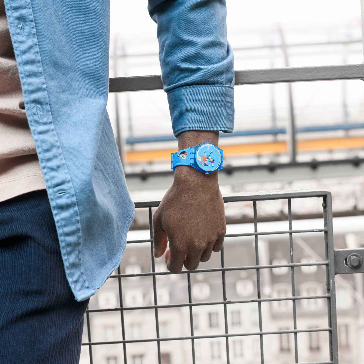 Blue silicone wristwatch on wrist, light-blue dial with colorful abstract design