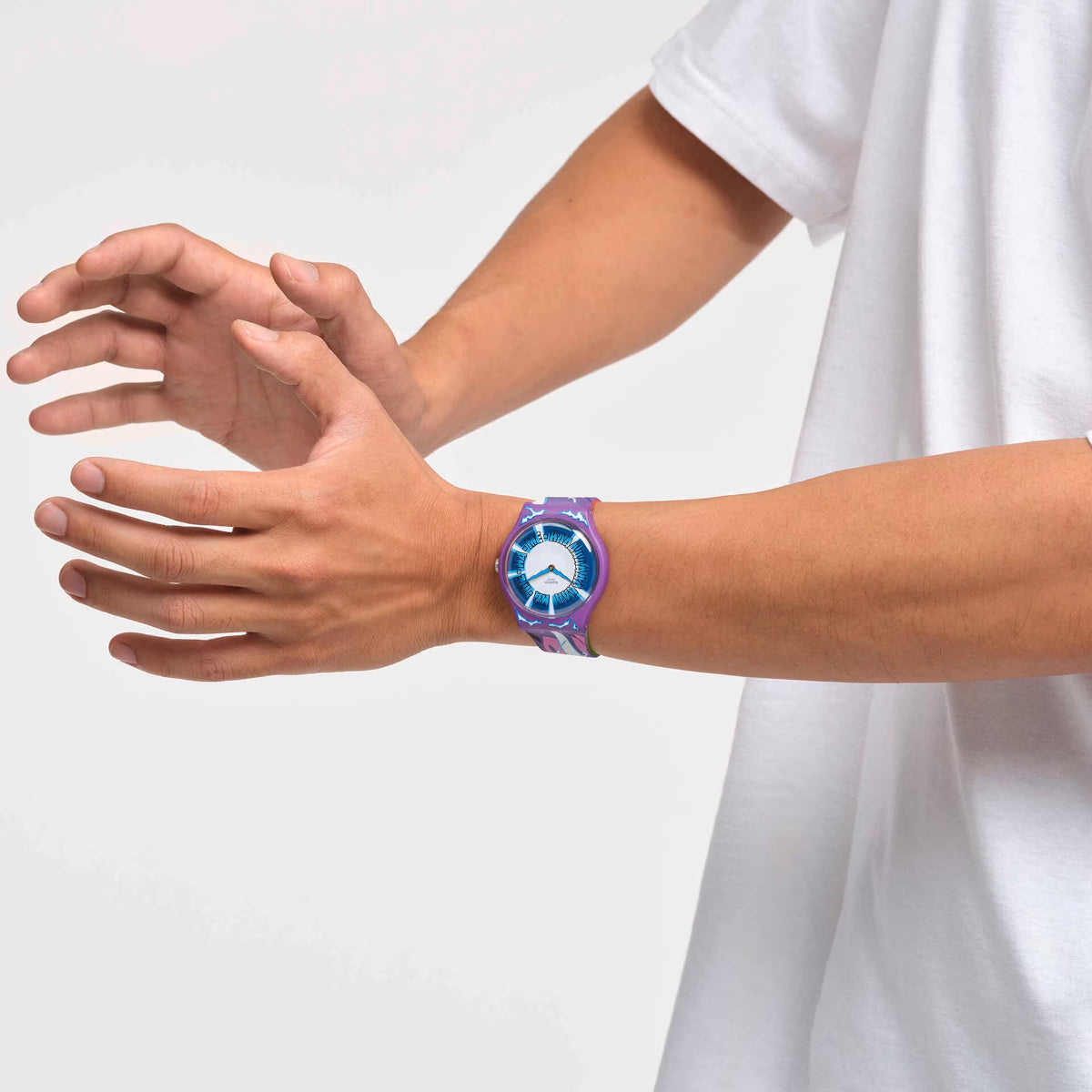 Silicone quartz watch with blue dial on purple patterned strap on forearm, close view