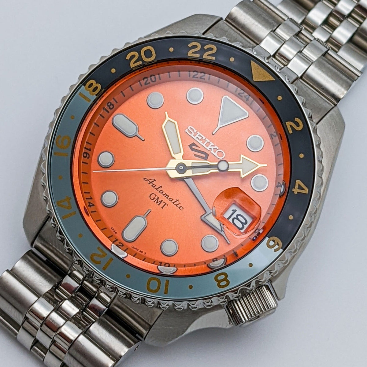Men's Seiko GMT watch close-up with orange dial and rotating bezel