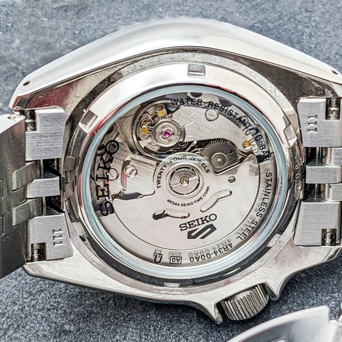 Men's Seiko GMT watch caseback with water-resistant text and stainless-steel bracelet