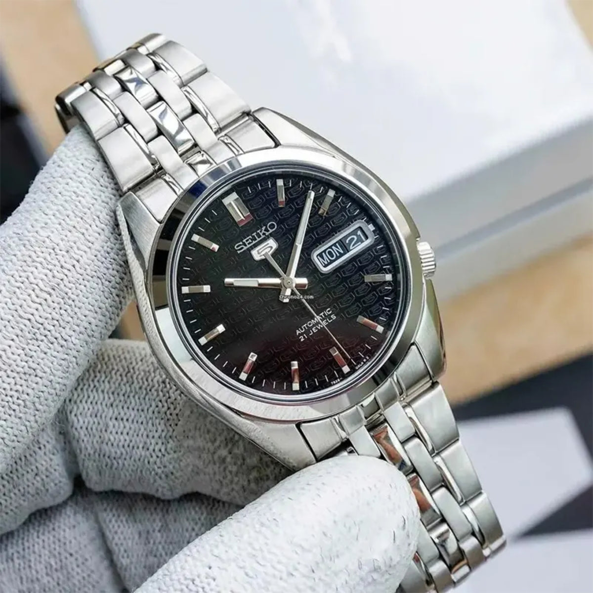 Men's stainless-steel watch on wrist with black dial, date window, and baton markers