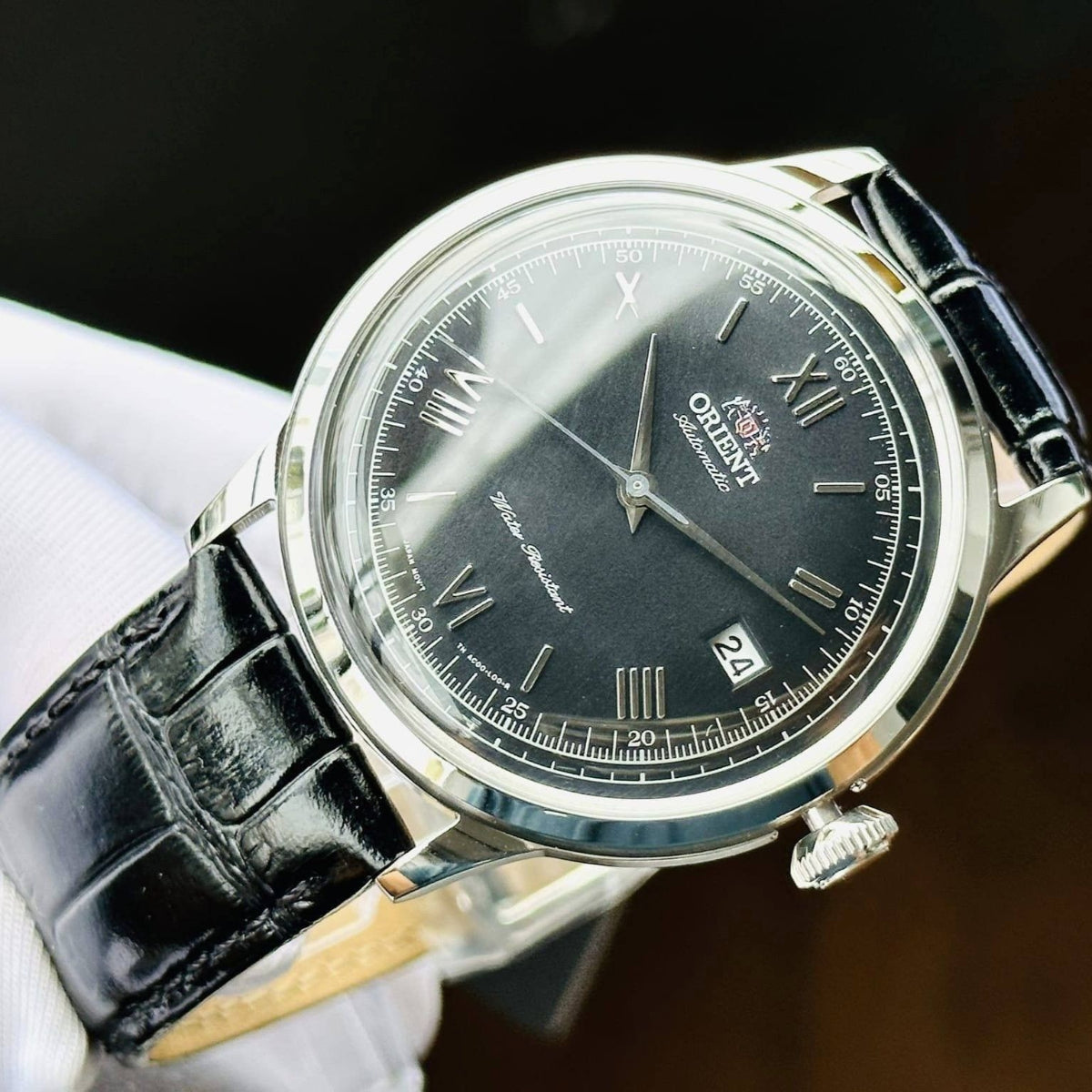 Automatic watch close-up with black leather strap and black dial with Roman numerals