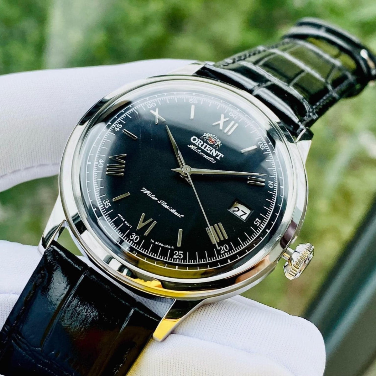 Automatic watch with black dial, Roman numerals, and dark green leather strap