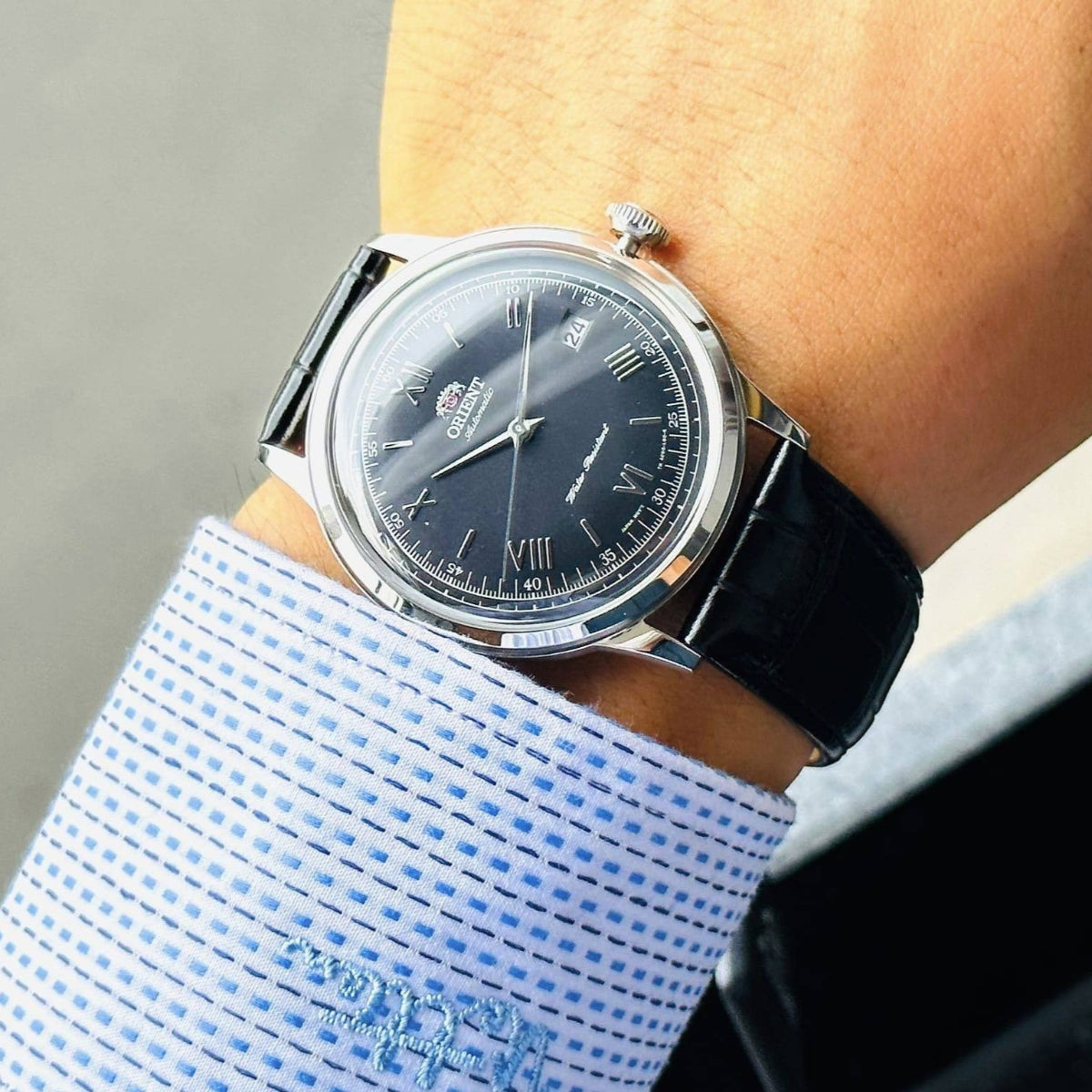 Men's automatic watch with black dial and black leather strap on a wrist