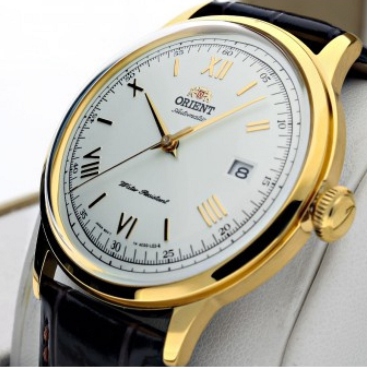Men's automatic wristwatch angled view, gold case, white dial, black leather strap