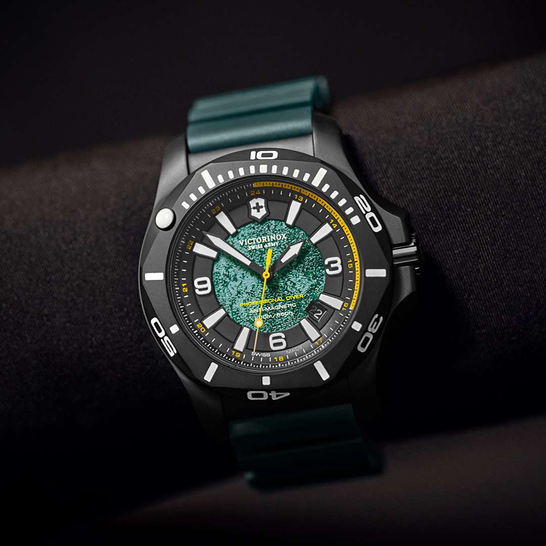 Men's dive watch close-up with black case, green dial texture, and dark teal strap