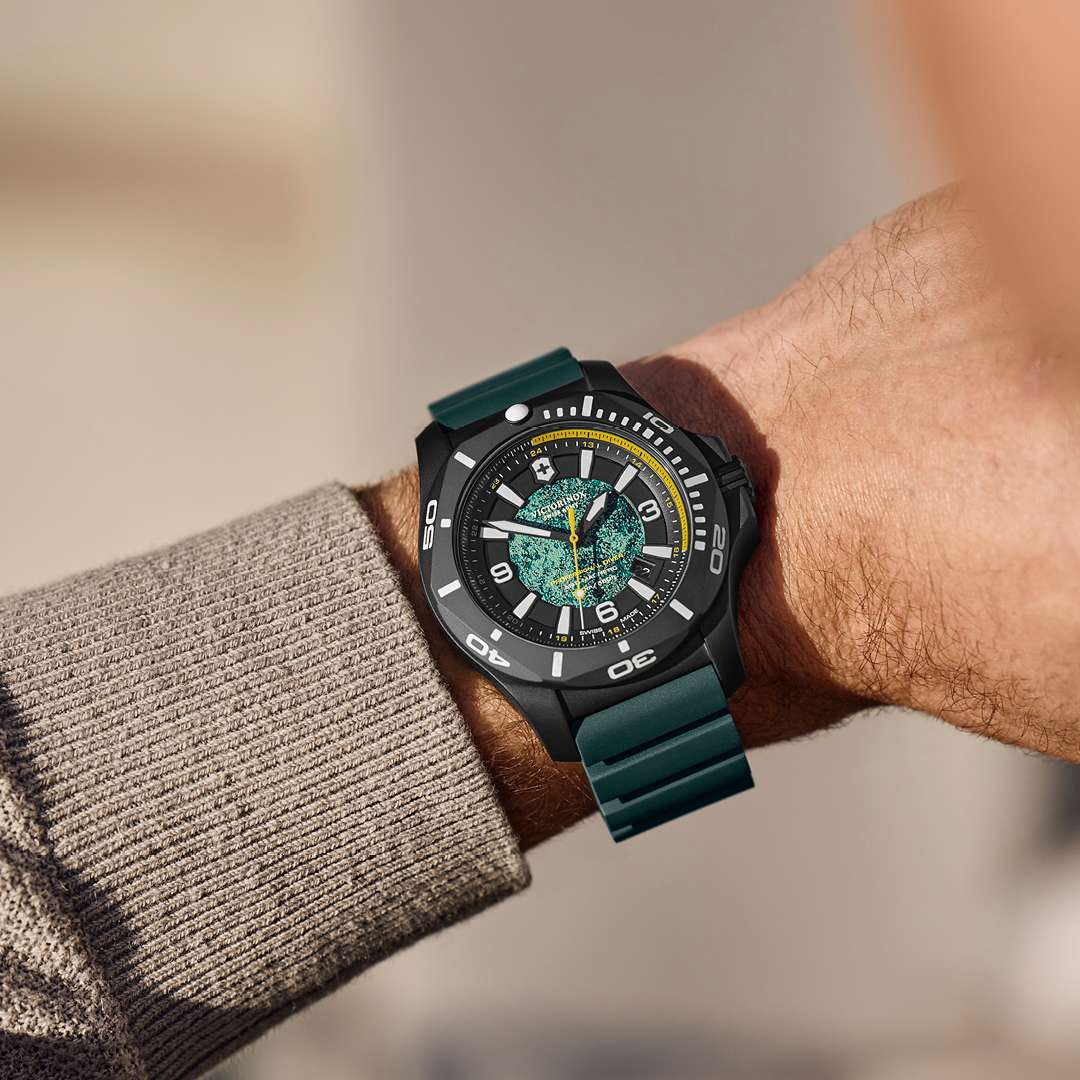 Men's dive watch worn on wrist with dark teal rubber strap and green textured dial