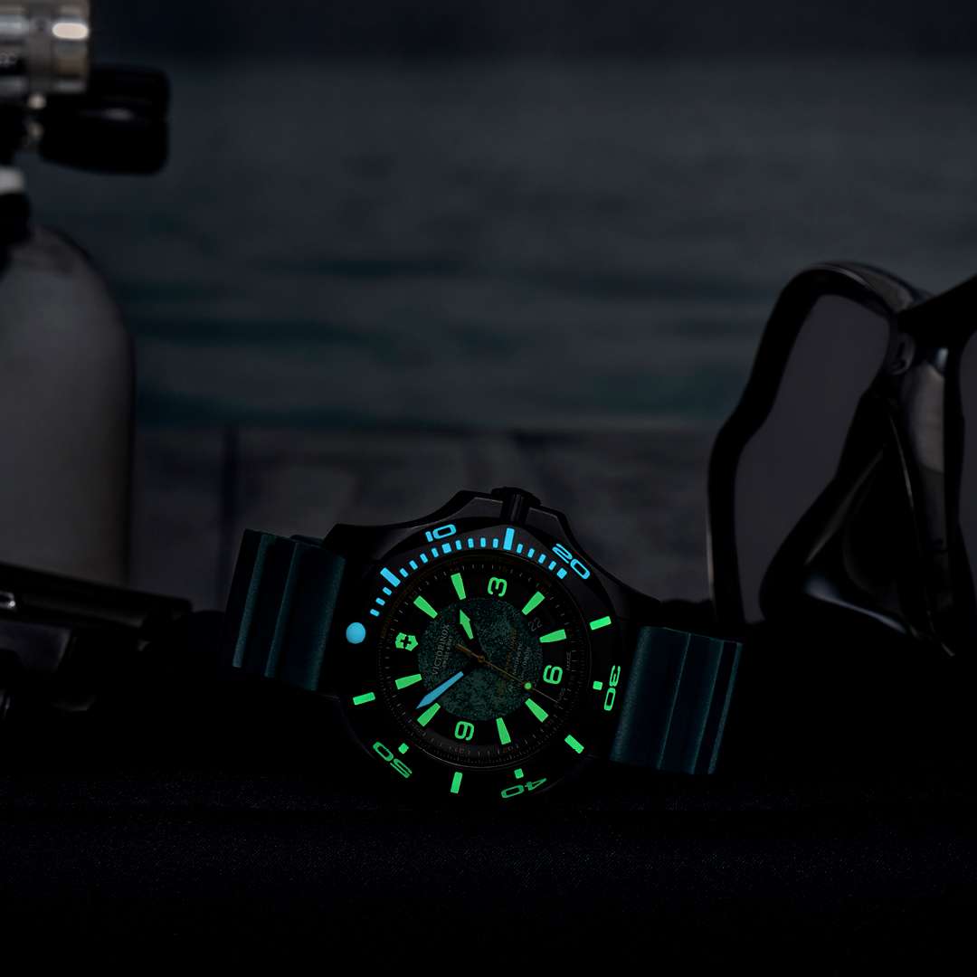 Men's dive watch at night with glowing bezel markers on dark teal rubber strap