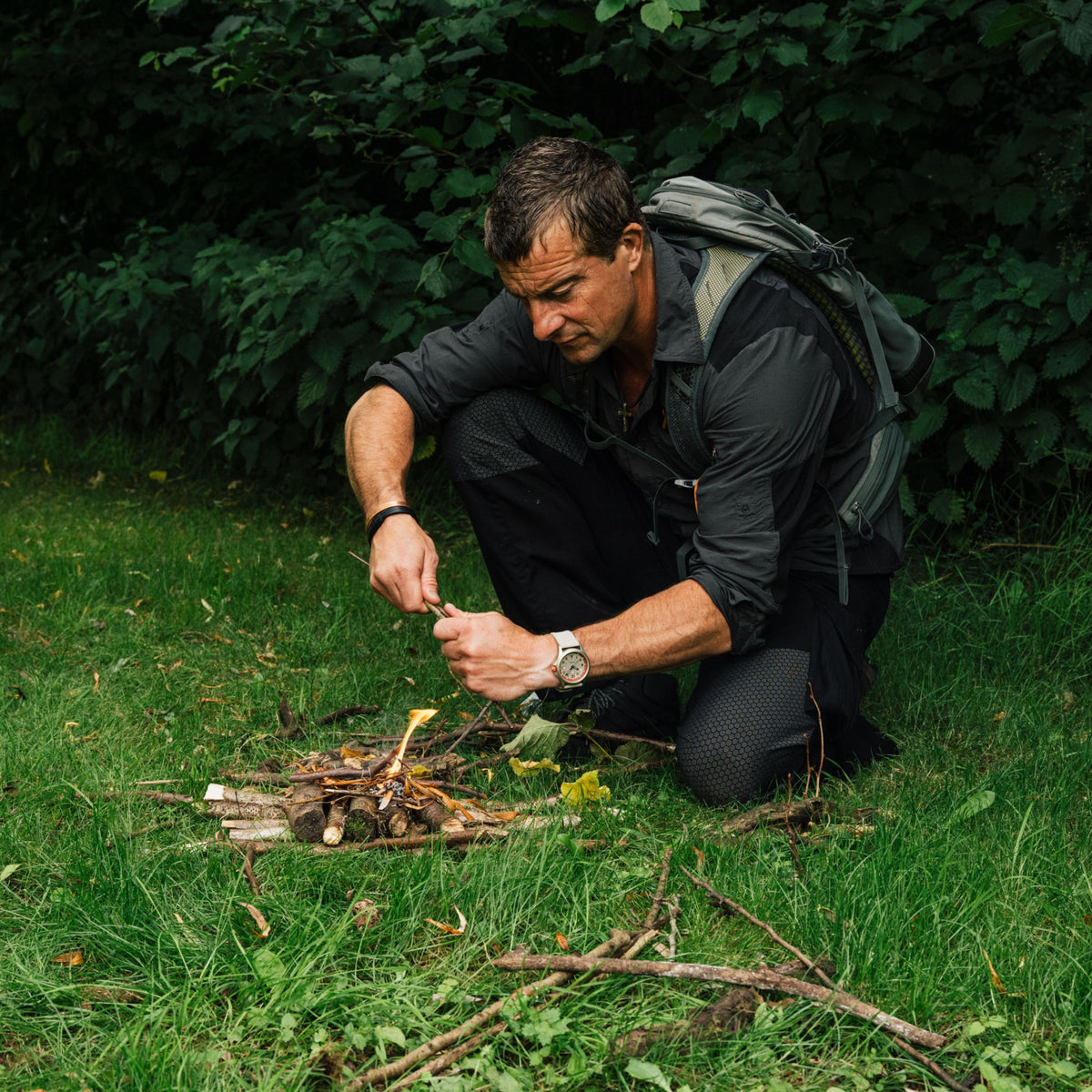Bear Grylls starting a campfire outdoors with the rugged Luminox Bear Grylls Survival XB.3717 quartz timepiece visible on his wrist