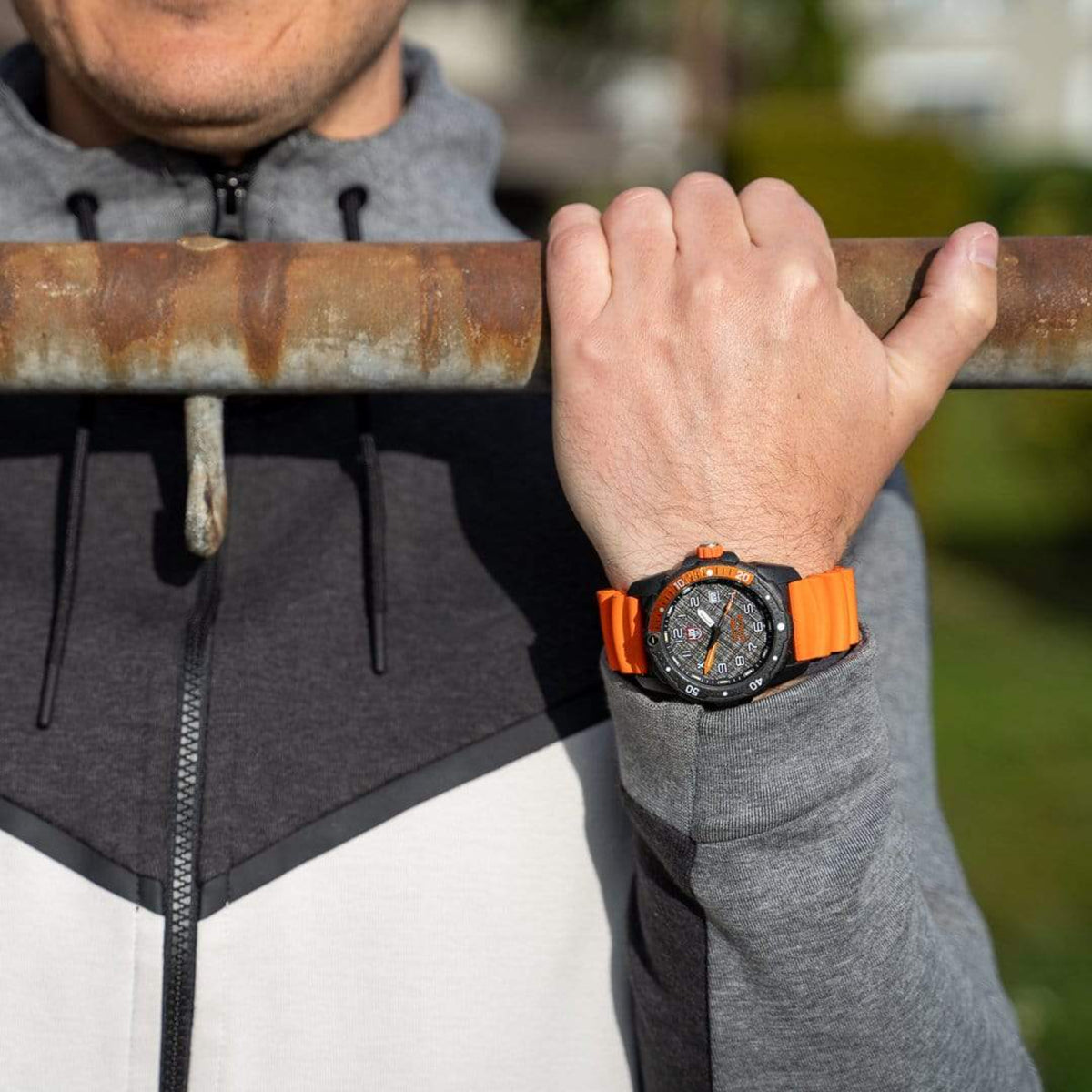 Men's quartz watch on wrist with orange rubber strap and black dial