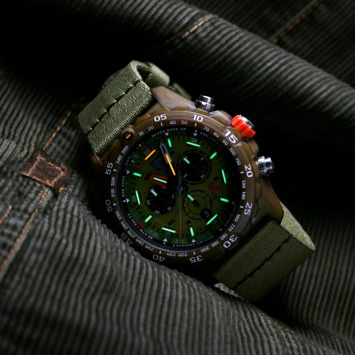 Green dial chronograph mens quartz watch with olive fabric strap and metal bezel.