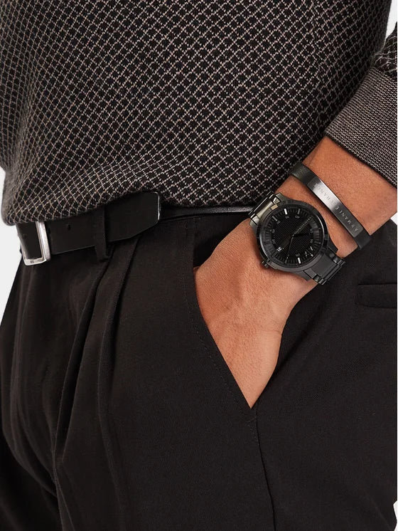 Close-up of a wrist wearing an all-black Armani Exchange watch paired with a black branded AX cuff bracelet