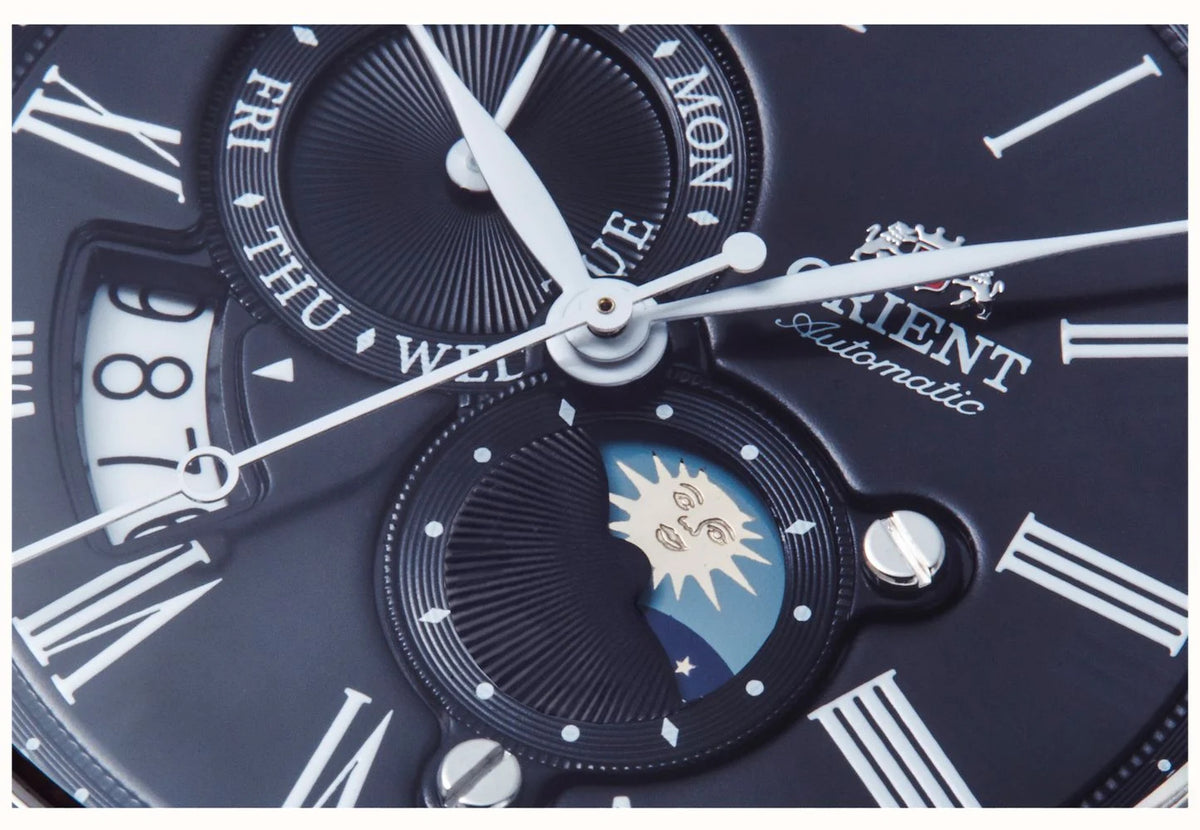 Close-up of men's watch dial with Roman numerals, sun-moon subdials, dark hands