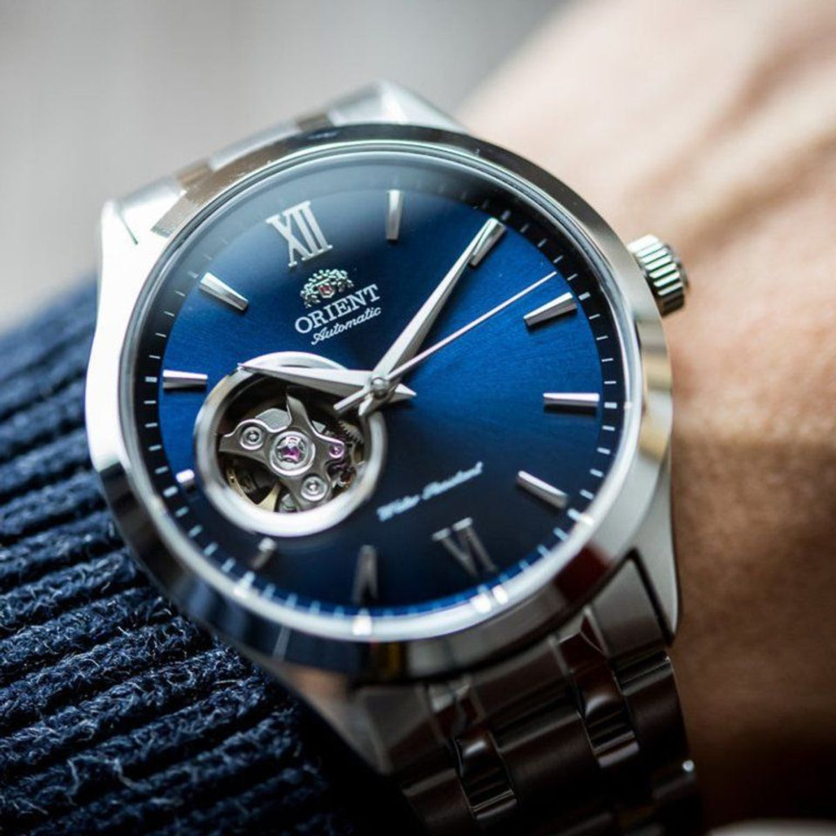 Orient Contemporary automatic watch on wrist with blue dial and open-heart movement, steel bracelet