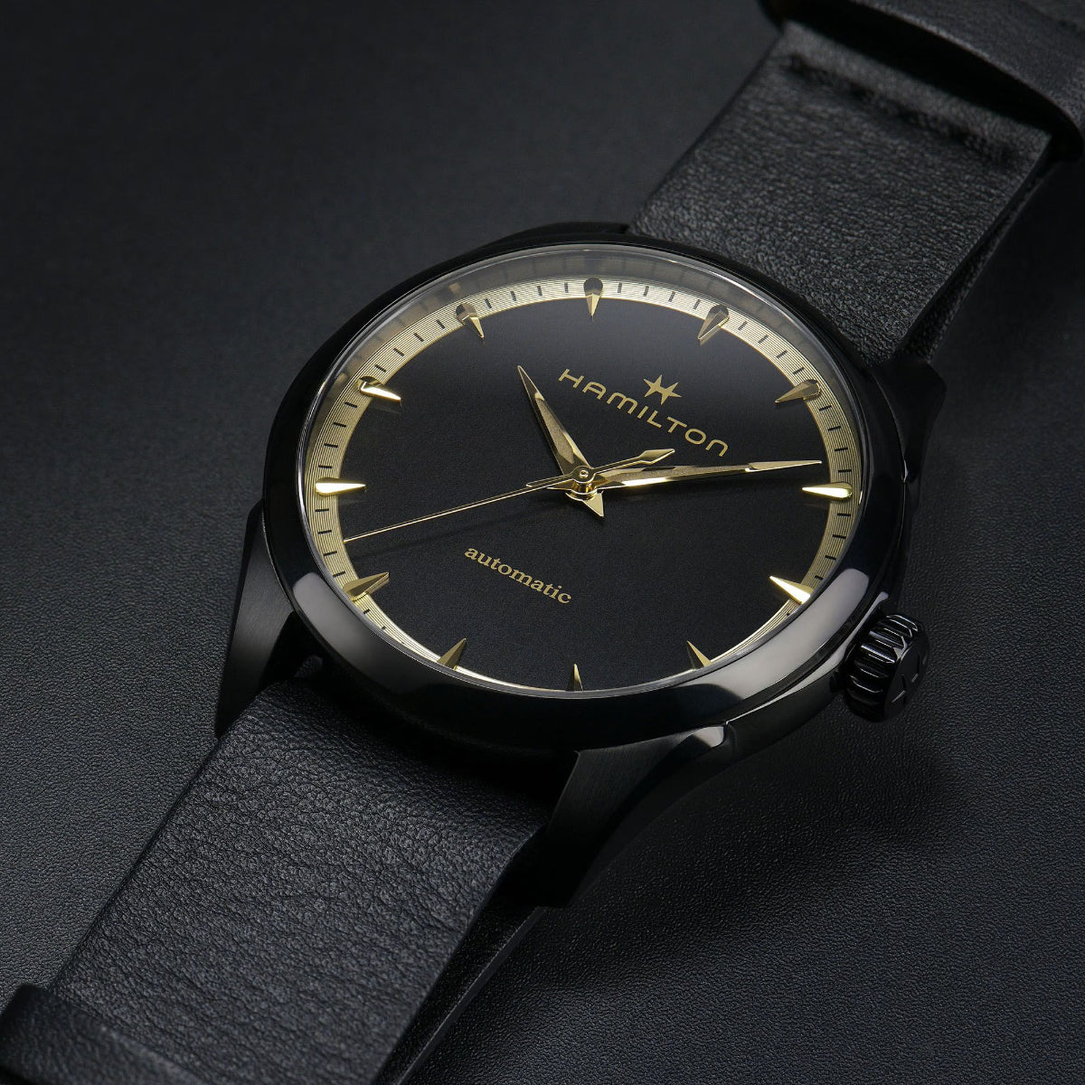 Black dial automatic watch with gold markers and hands, on black leather strap