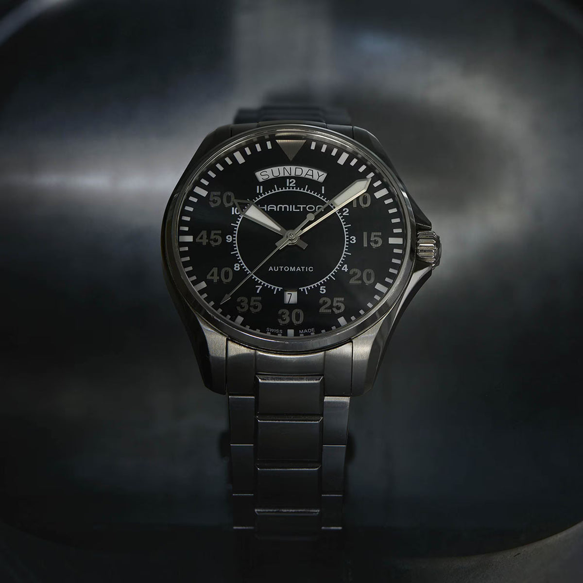 Head on view of the Hamilton Khaki Aviation H64615135 mens watch under soft atmospheric lighting
