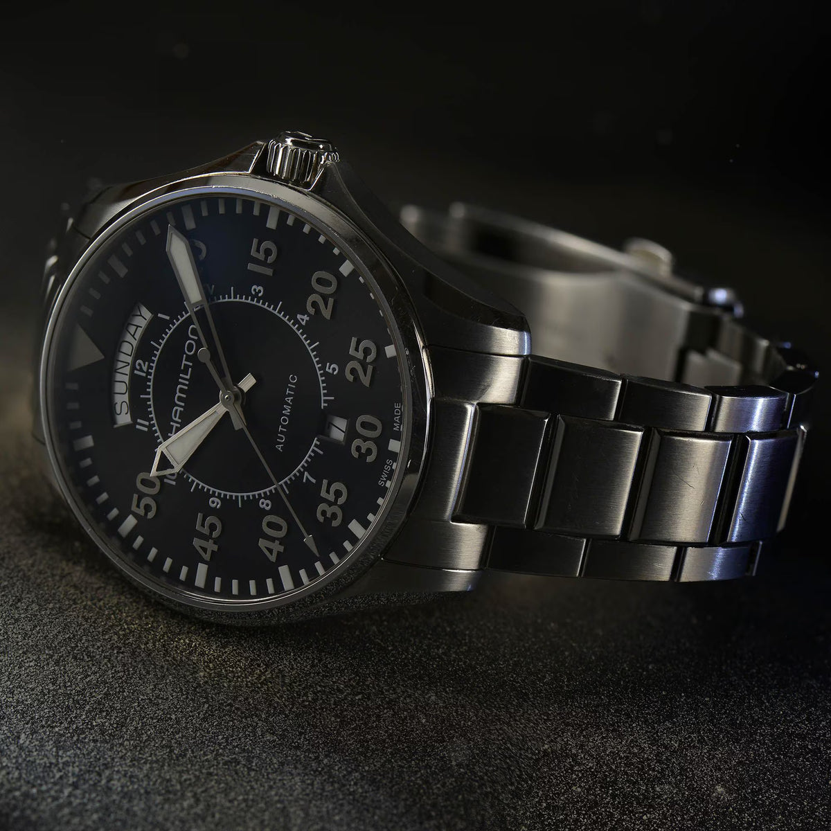 Close-up highlighting the luminous hands, minute track, and steel strap of the Hamilton Khaki Aviation H64615135