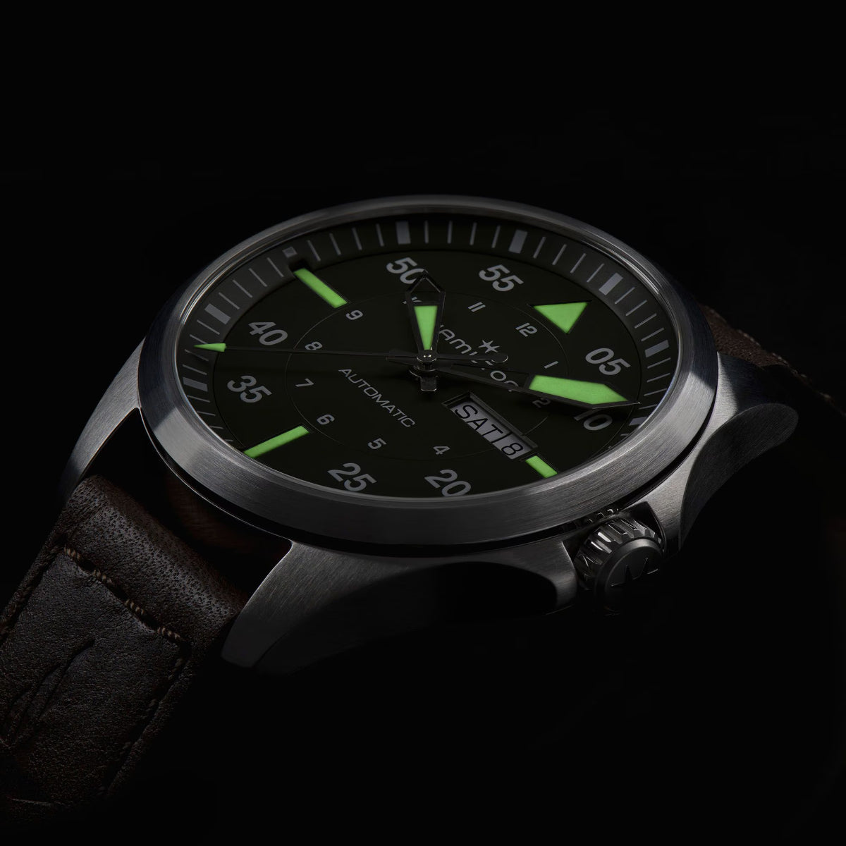 Hamilton Khaki Aviation H64635560 automatic watch low-light view displaying green dial, luminous hands, and glowing indices