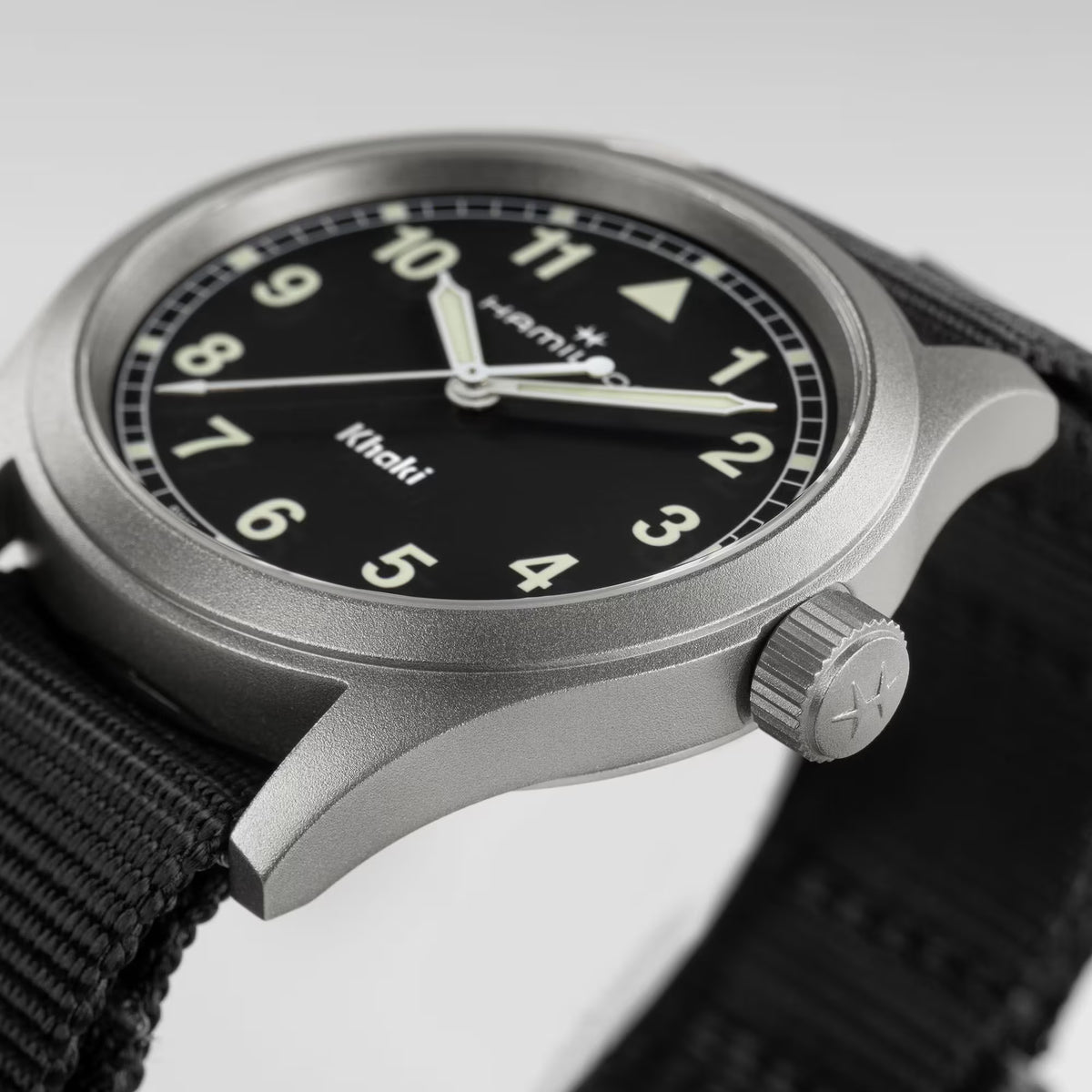 Hamilton Khaki Field H69401430 watch side angle showing matte steel case, crown detail, and woven black fabric strap